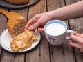 The girl`s hand takes a slice of bread spread with peanut butter, in her other hand a mug of milk Royalty Free Stock Photo