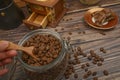 The girl`s hand takes a wooden spoon of coffee beans from a glass jar, a coffee grinder, pieces of chocolate on a wooden Royalty Free Stock Photo