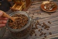 The girl`s hand takes a wooden spoon of coffee beans from a glass jar, a coffee grinder, pieces of chocolate on a wooden Royalty Free Stock Photo