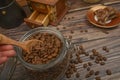 The girl`s hand takes a wooden spoon of coffee beans from a glass jar, a coffee grinder, pieces of chocolate on a wooden Royalty Free Stock Photo