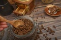 The girl`s hand takes a wooden spoon of coffee beans from a glass jar, a coffee grinder, pieces of chocolate on a wooden Royalty Free Stock Photo