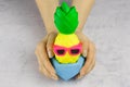 Girl`s hands with bright pineapple with sunglasses