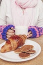 Girl`s hands with cup of coffee and a plate with croissant and cookies