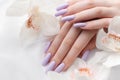 Girl`s hands with delicate purple manicure and orchid flowers