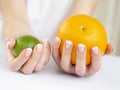 Girl`s Hands with French Manicure on Nails Holding a Fresh Summer Orange and Limet Fruits Royalty Free Stock Photo