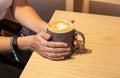 Girl`s hands holding a cup of coffee, ripped jeans. Fashion manicur