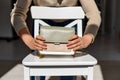 the girl's hands are holding a green-white handbag on the background of a white chair with a bright sun