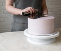 Girl`s hands line with a cream spatula on a round cake. decorating the holiday cake Royalty Free Stock Photo