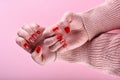 Girl`s hands with a red manicure on her nails are on a pink background Royalty Free Stock Photo