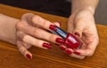 Girl's hands with red nail Polish holding a bottle with varnish Royalty Free Stock Photo