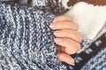 Girl`s hands on soft knitted sweater, close up. Modern style tender pastel pink nail polish. Beautiful women manicure. Hand care