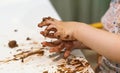 The girl`s hands are stained with brown chocolate. Dirty children`s hands. The child made a mess, smeared a chocolate cake on the Royalty Free Stock Photo