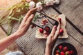 Girl`s hands taking photo of breakfast with strawberries by smartphone. Healthy breakfast, Clean eating, vegan food concept. Royalty Free Stock Photo