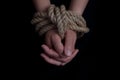 girl& x27;s hands tied with a rope on a black background