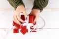 Girl`s hands unwrapping Christmas, birthday or Valentines red gift on a white background