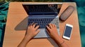 Girl`s hands using laptop with smart phone on desk in the garden interior. Royalty Free Stock Photo