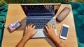 Girl`s hands using laptop with smartphone and camera on desk in the garden interior, top view image concept Royalty Free Stock Photo