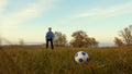 Girl`s leg hits soccer ball man catches ball. family plays football in park. dad and daughter play ball on the field. Royalty Free Stock Photo