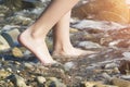 The girl`s legs go into the sea surf on a pebble beach in the sun. The concept of tourism Royalty Free Stock Photo