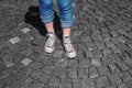 Girl's legs in gumshoes on pavement