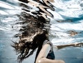 A girl`s long hair flowing underwater and reflections on the undersurface of the water