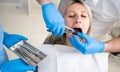 girl& x27;s mouth in the bib of the patient in the dental clinic. A dentist in blue latex gloves removes her tooth with a