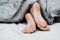 girl's toes covered with bed sheet. crop view of a girl in the bed Royalty Free Stock Photo