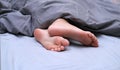 Girl`s toes covered with bed sheet. crop view of a girl in the bed Royalty Free Stock Photo