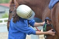 Girl saddling her horse on the farm