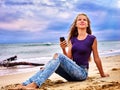 Girl on sand near sea call help by phone. Royalty Free Stock Photo