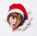 Girl with santa cap looking out of a hole in a paper Royalty Free Stock Photo