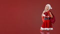 Girl in Santa Claus costume with a bag of gifts on a red backgro Royalty Free Stock Photo