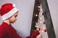 A girl in a Santa Claus hat near a Christmas tree. The Christmas tree is decorated with toys and garlands. New Year Royalty Free Stock Photo