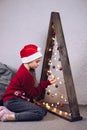 A girl in a Santa Claus hat near a Christmas tree. The Christmas tree is decorated with toys and garlands. New Year Royalty Free Stock Photo