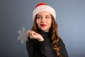girl in santa hat portrait with big silver snowflake toy posing on gray color background, christmas holiday concept, happy and Royalty Free Stock Photo