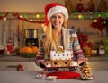 Girl in santa hat showing christmas cookie house