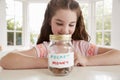 Girl Saving Pocket Money In Glass Jar At Home