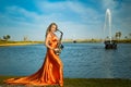 Girl with sax smiles, flirts. Happy blonde woman with big bust plays, performs on goldy saxophone in beautiful dress Royalty Free Stock Photo