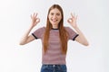 Girl saying okay, having no worries. Attractive, pleasant caucasian woman in striped t-shirt show ok sign and smiling in