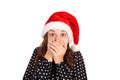 Girl scared and closes the mouth with her hands. emotional girl in santa claus christmas hat isolated on white background. holiday Royalty Free Stock Photo