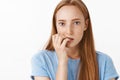 Girl scared of not knowing what happen. Portrait of concerned focused beautiful ginger girl with freckles biting