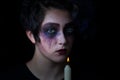 Girl in scary makeup with lite candle on black background