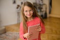 Girl of school age with long hair in pink sweater, glasses, notebook in her hands