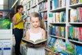 Girl in school age looking in open chosen book