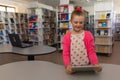 Girl in school library using tablet, smiling and exploring digital content, copy space