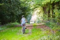 Girl in school uniform and cycle helmet riding bike along a tree lined country track