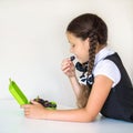 A girl in a school uniform eats grapes from a lunchbox.