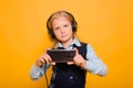 Girl in a school uniform with headphones on her head listens to music and holds a smartphone in her hands Royalty Free Stock Photo