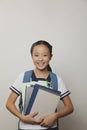 Girl in school uniform smiling and holding bunch of notebooks and digital tablet, Studio shot