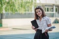 Girl schoolgirl compares the tablet and textbooks. The child is holding a tablet and books. The student has an idea. The girl in Royalty Free Stock Photo